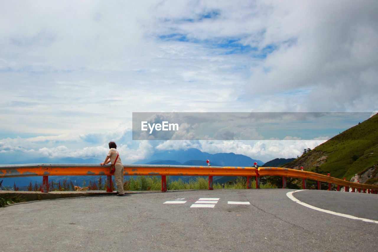 REAR VIEW OF A MAN OVERLOOKING CALM SEA