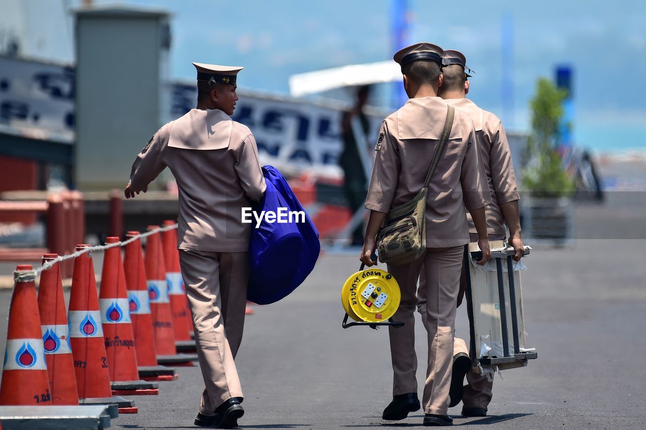 REAR VIEW OF PEOPLE WALKING ON STREET