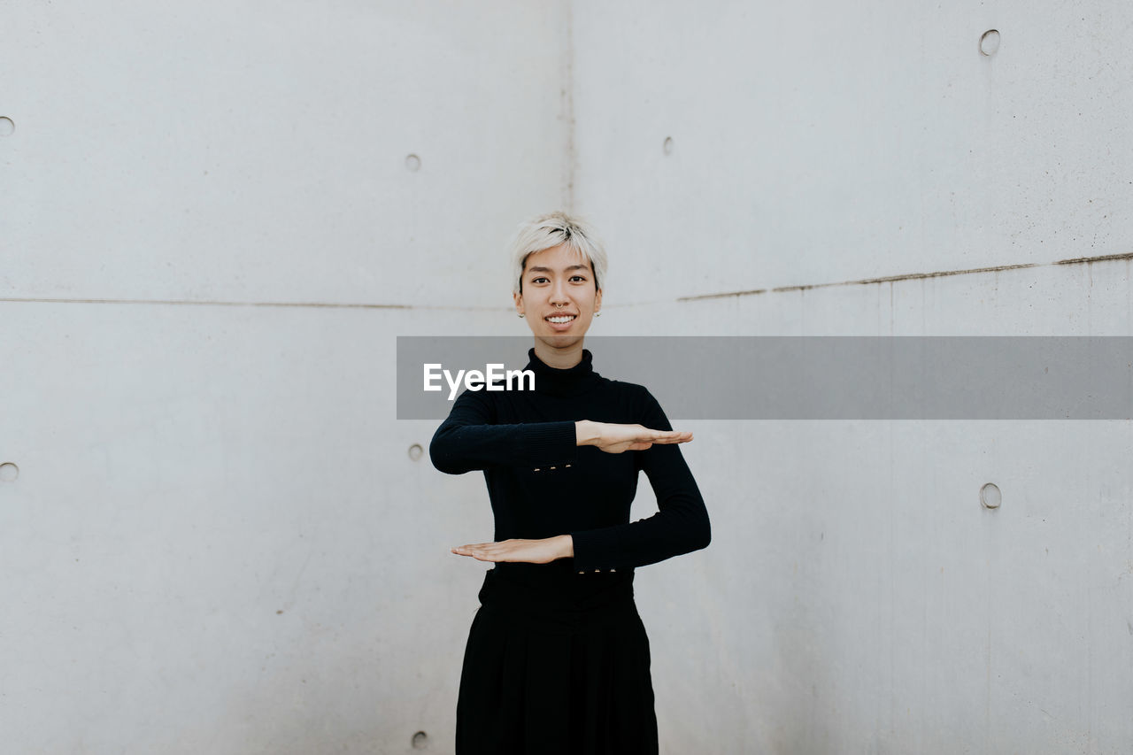 FULL LENGTH PORTRAIT OF WOMAN STANDING AGAINST WALL