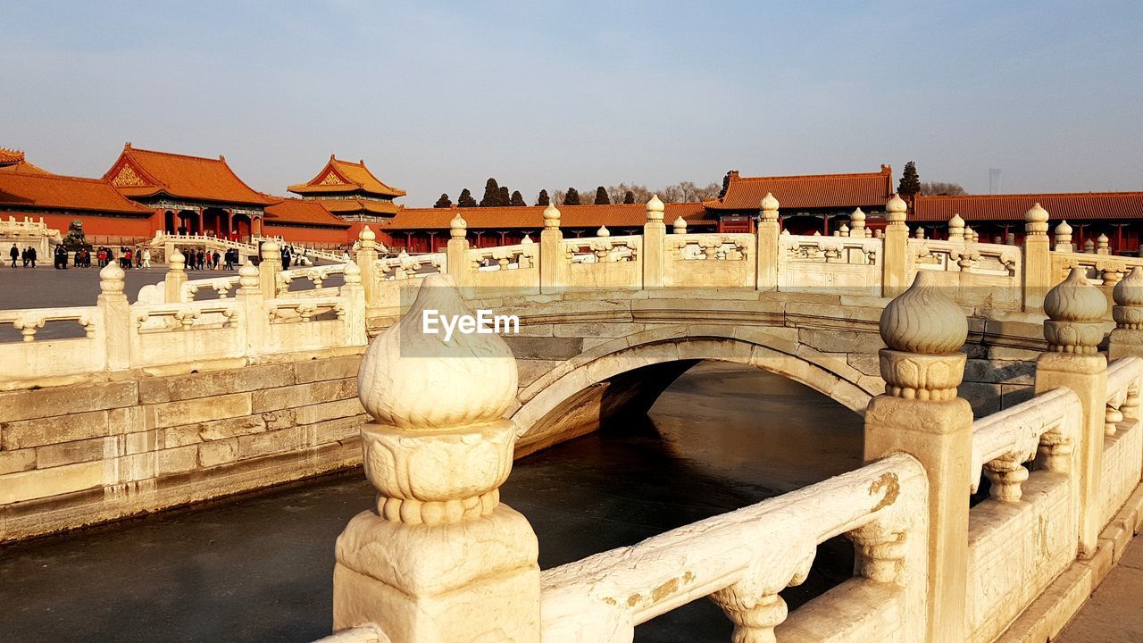Arch bridge over river against palace - forbidden city in bejing