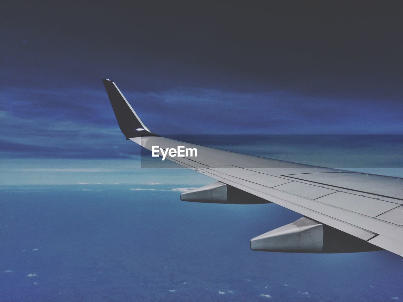 Cropped image of airplane wing flying over clouds