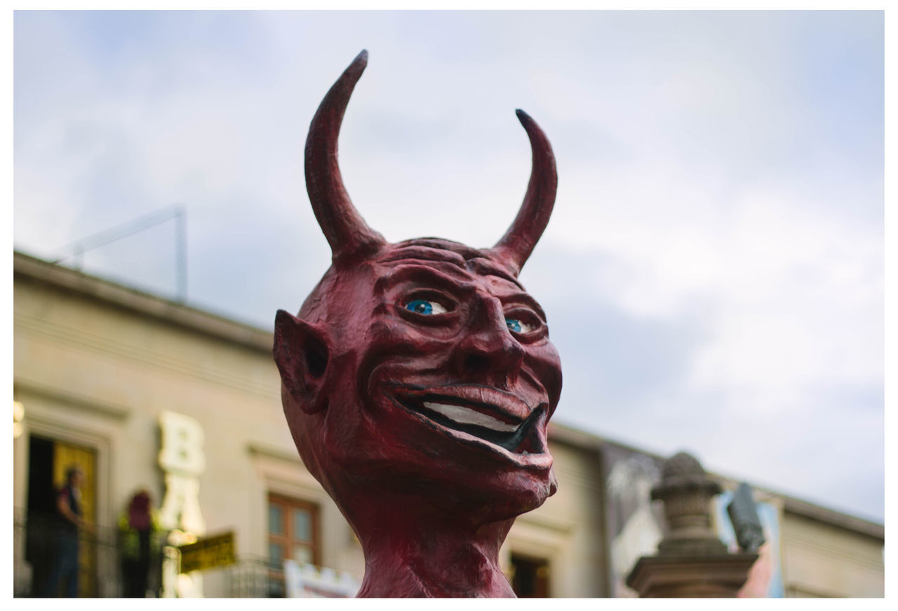 Low angle view of devil statue against sky