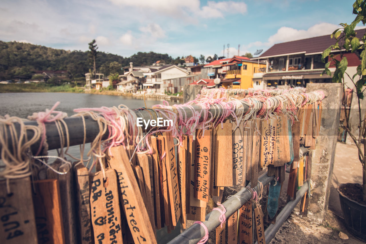 Close-up of messages tied on railing against sky