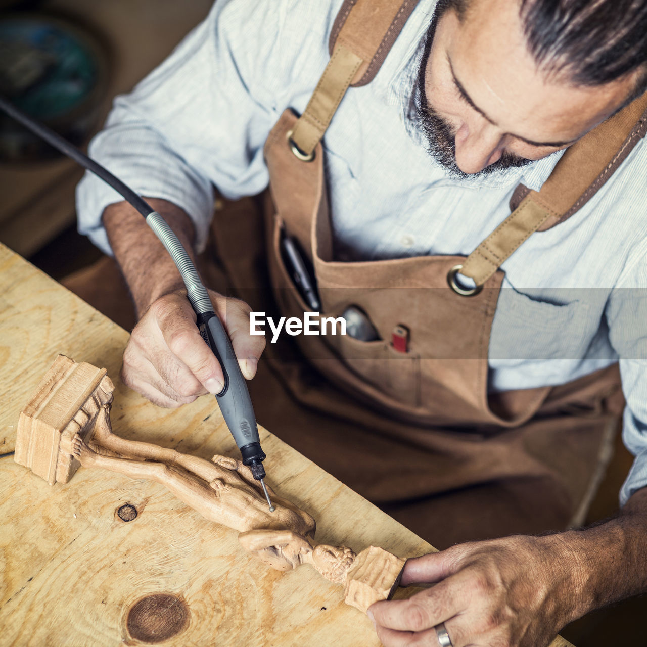 Carpenter carving on figurine in workshop