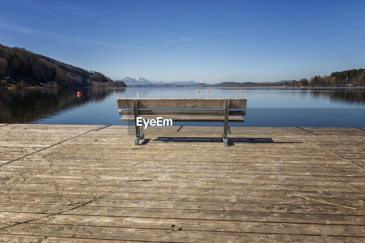 Empty pier on lake against blue sky