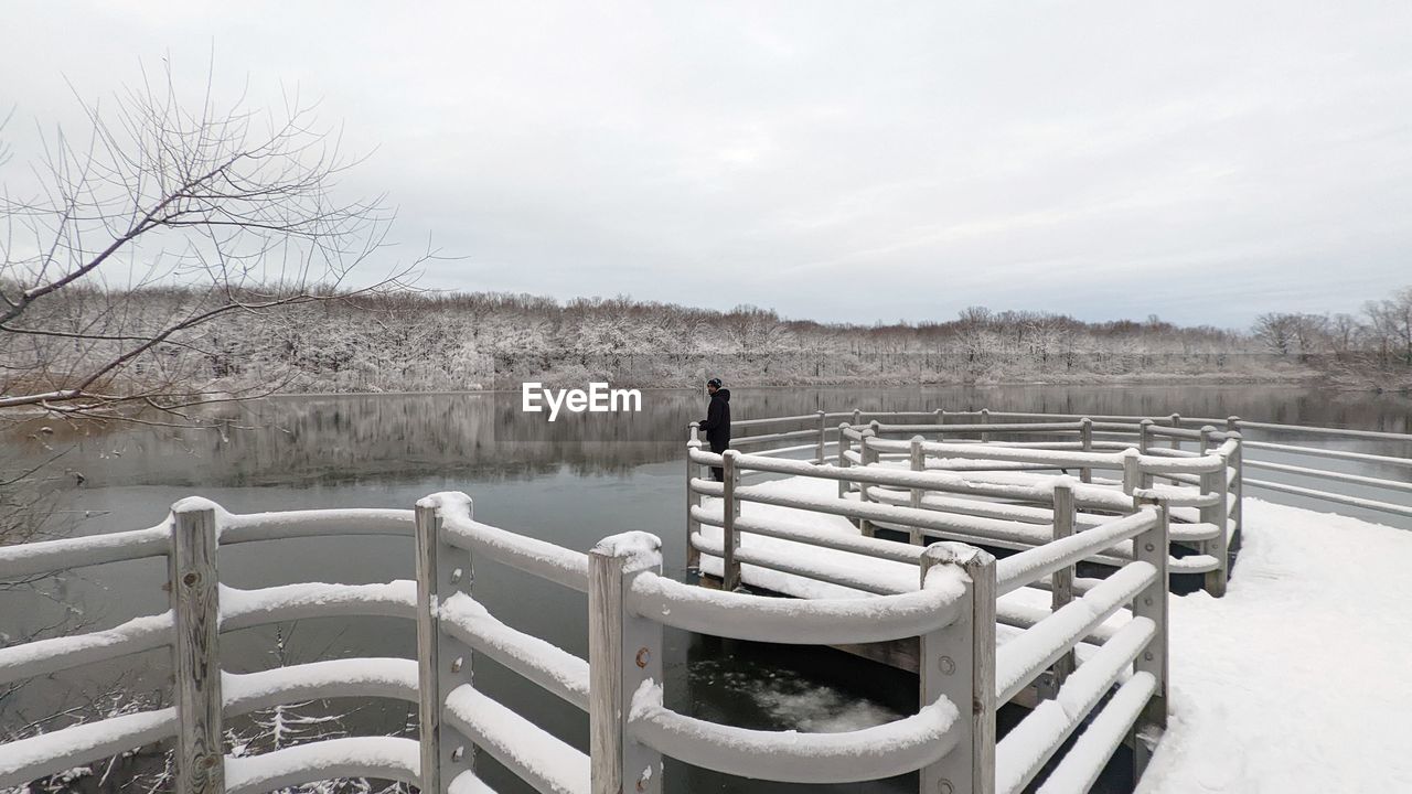 winter, snow, nature, sky, water, split-rail fence, tranquility, cold temperature, seat, wood, tranquil scene, scenics - nature, day, railing, tree, beauty in nature, bare tree, no people, plant, lake, landscape, non-urban scene, environment, outdoors, empty, furniture, land, bench, fence, cloud