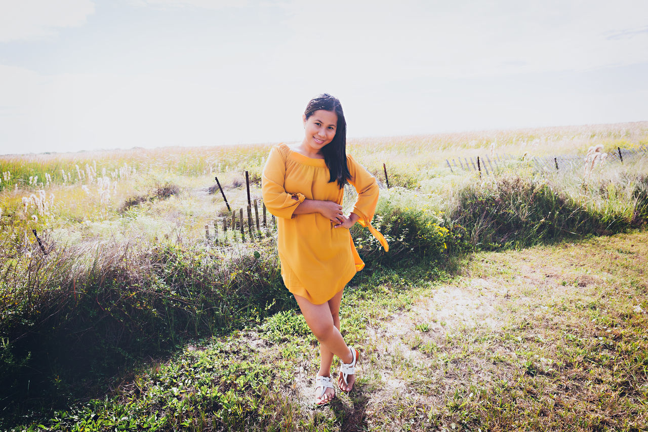 Portrait of woman standing on grassy field during sunny day