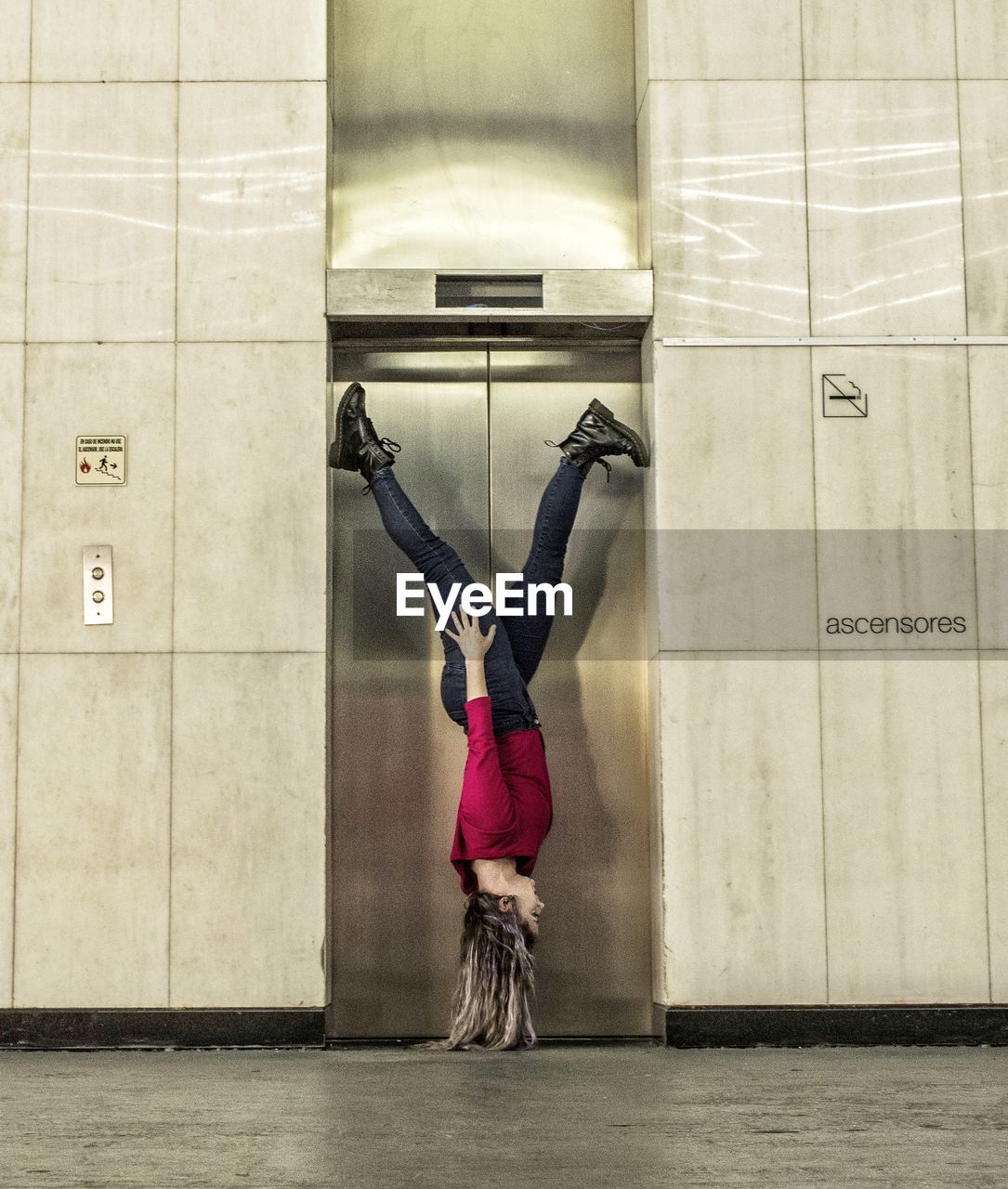 Side view of woman levitating upside down by elevator