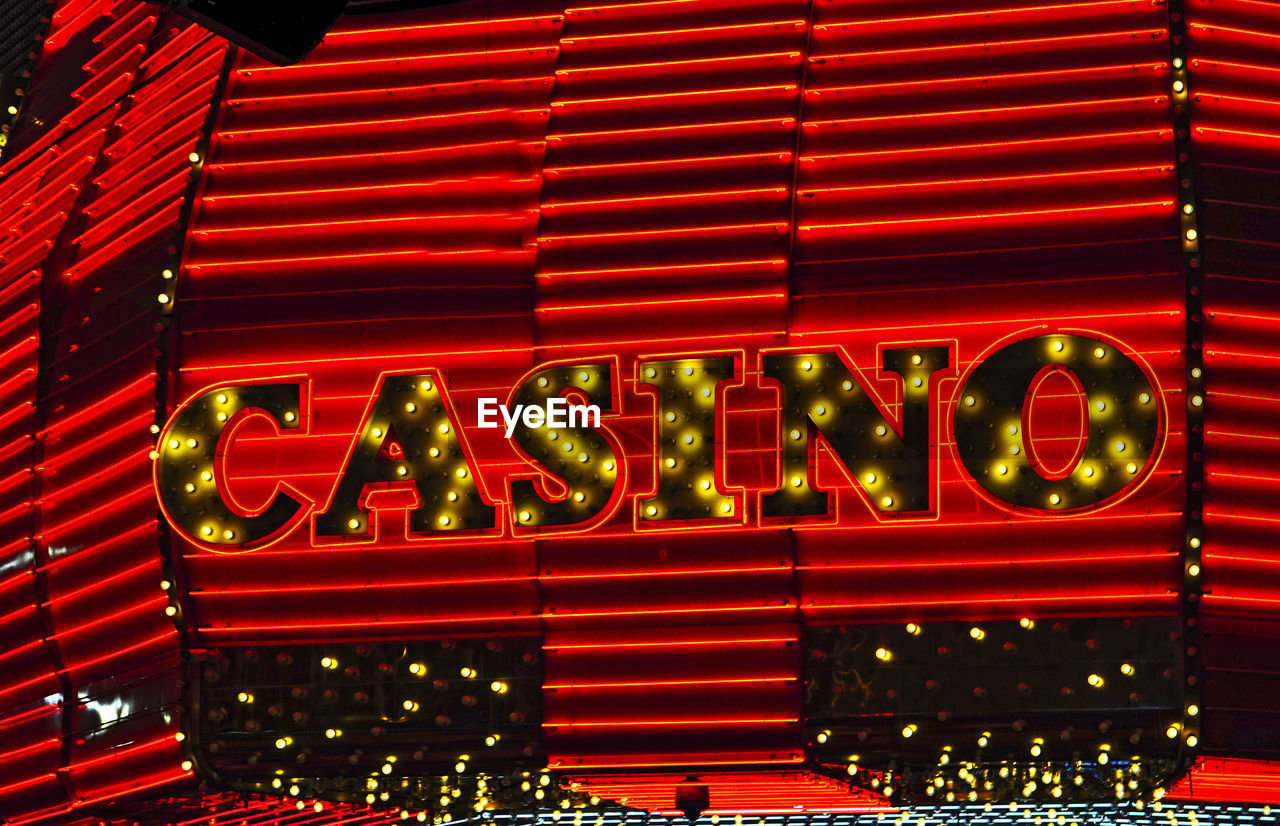 Illuminated text on red wall in city at night