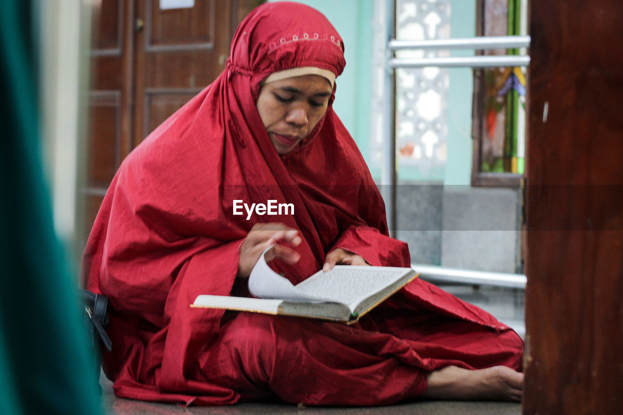 Portrait of young woman in muslim clothes reading the qur'an