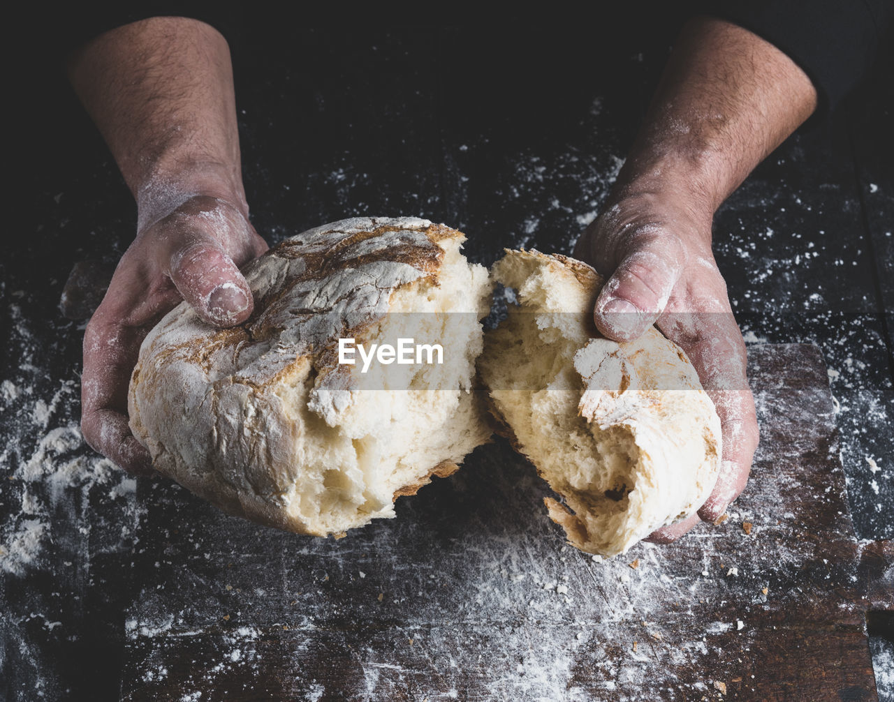 Close-up of person breaking bread at counter