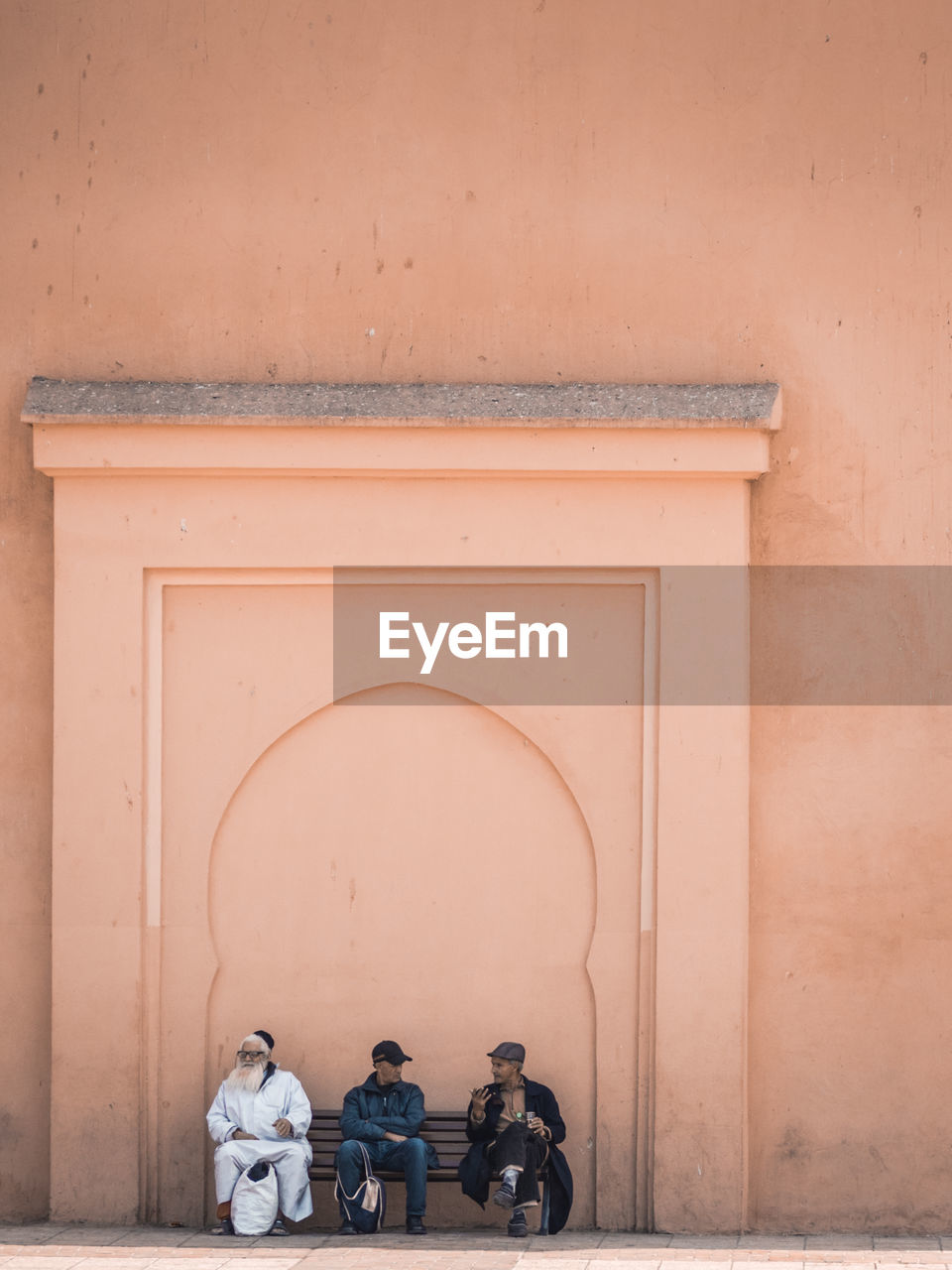 REAR VIEW OF MAN AND WOMAN STANDING AGAINST WALL