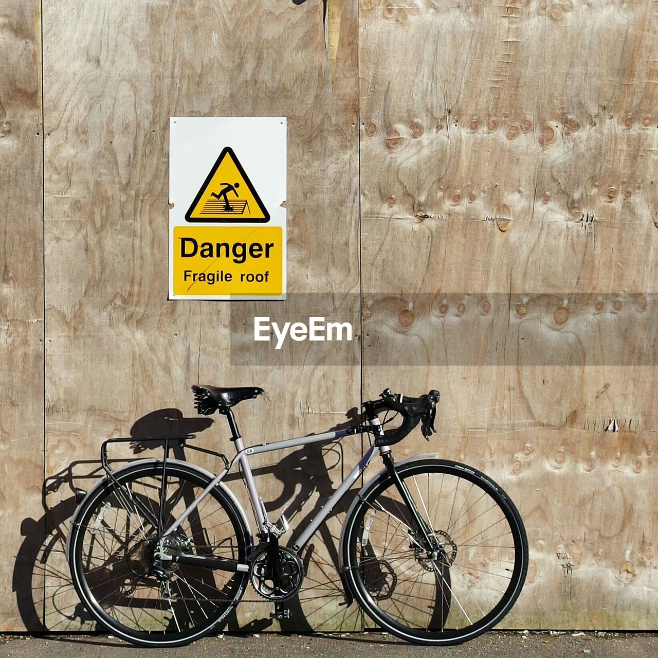 Bike leaning against wall with warning sign