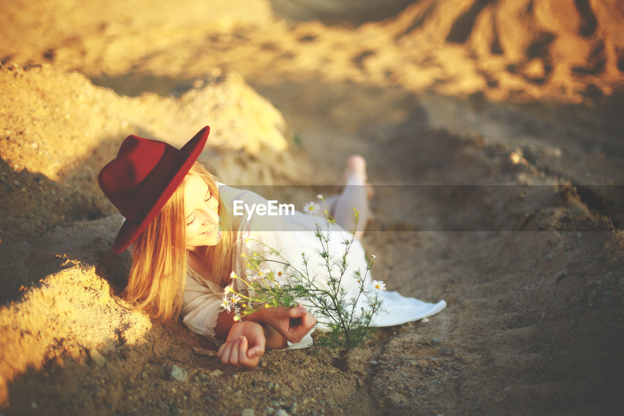 Young woman lying at beach by plant 