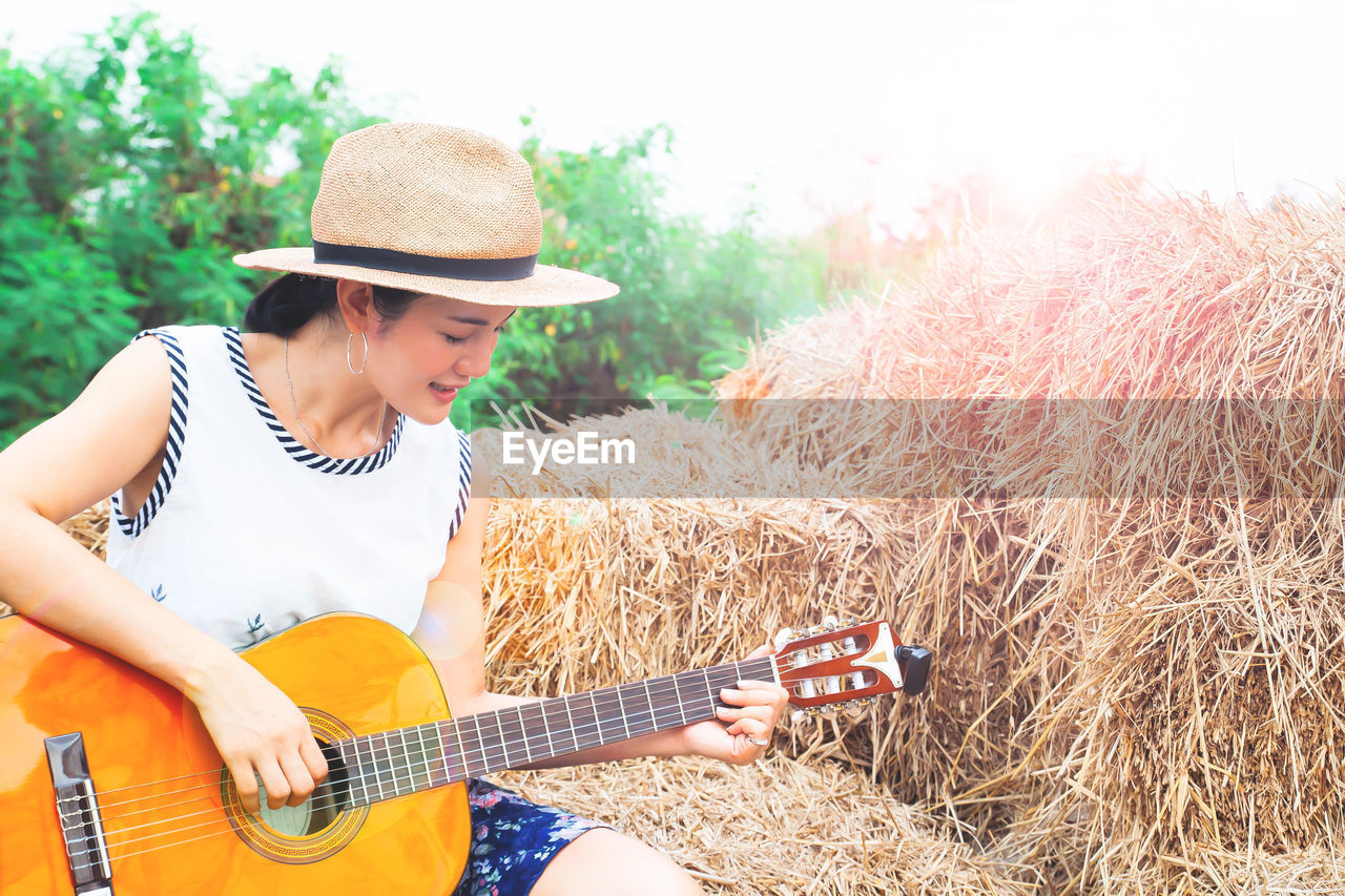 Woman playing guitar by hay