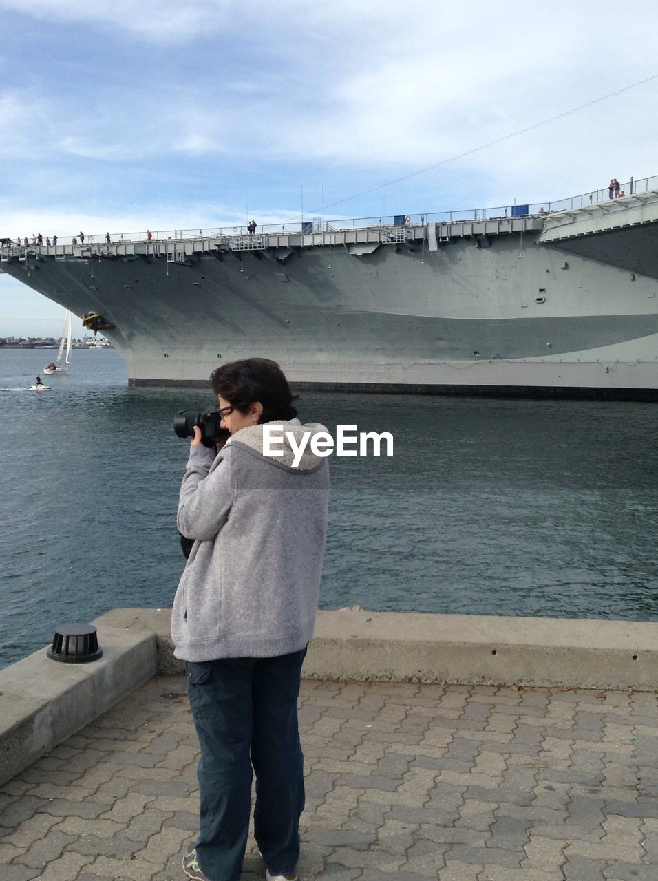 REAR VIEW OF MAN STANDING ON BRIDGE AGAINST SKY