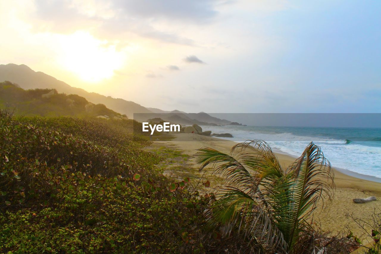 Scenic view of mountains against sea at sunset