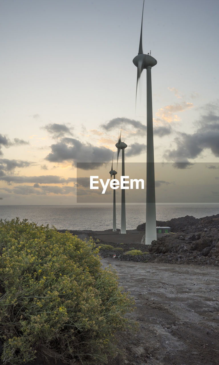 Windmills on beach against sky