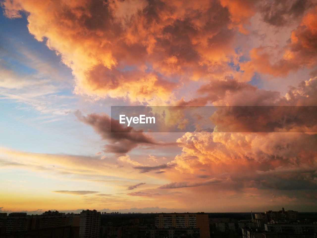 Scenic view of dramatic sky over city during sunset