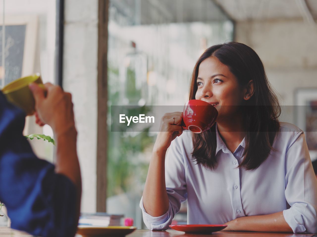 Close-up of young woman drinking coffee while looking away at cafe