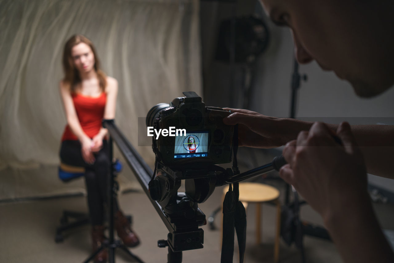 Midsection of man photographing woman in studio