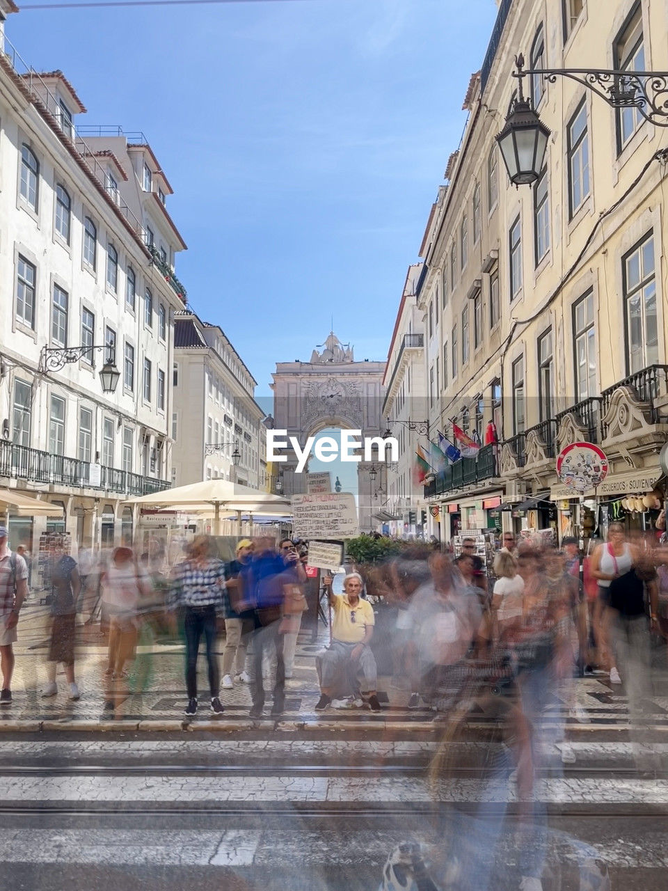 architecture, city, building exterior, built structure, street, group of people, road, large group of people, city street, crowd, city life, town, motion, travel destinations, building, urban area, walking, town square, cityscape, nature, adult, sky, blurred motion, men, travel, women, tourism, plaza, day, transportation, water, neighbourhood, outdoors, infrastructure, wet, downtown, lifestyles, business, business finance and industry