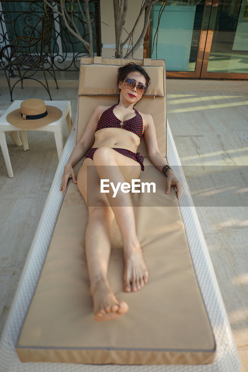 Portrait of woman lying on lounge chair at resort