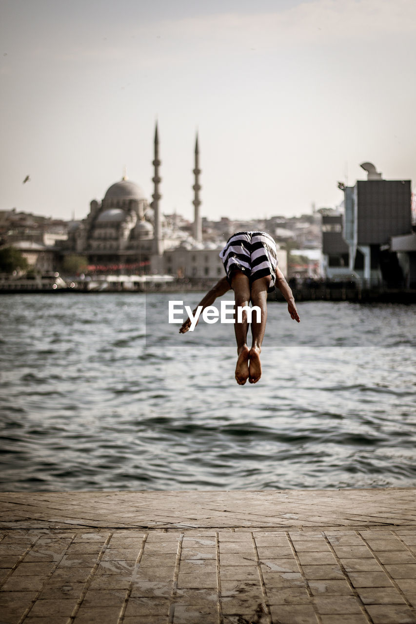 Rear view of woman jumping into river