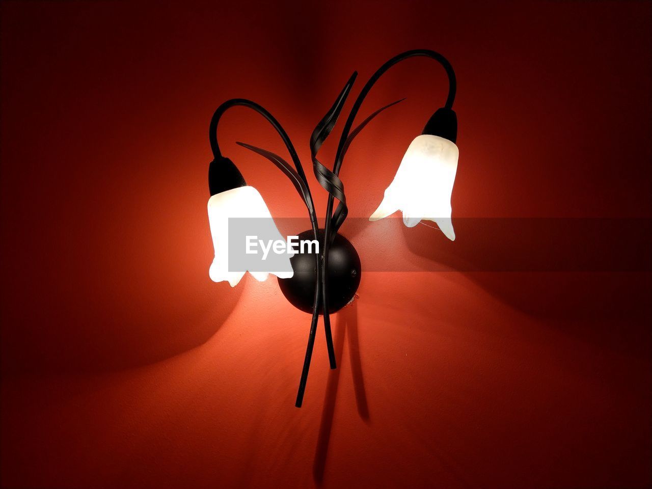 Low angle view of illuminated lamps on red wall