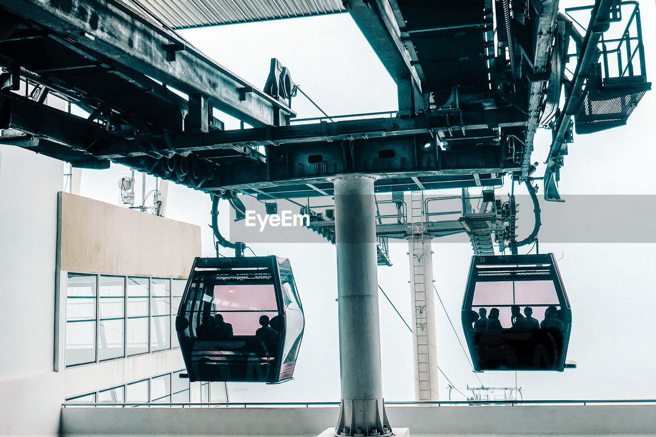 Silhouette people sitting in overhead cable car seen from glass window