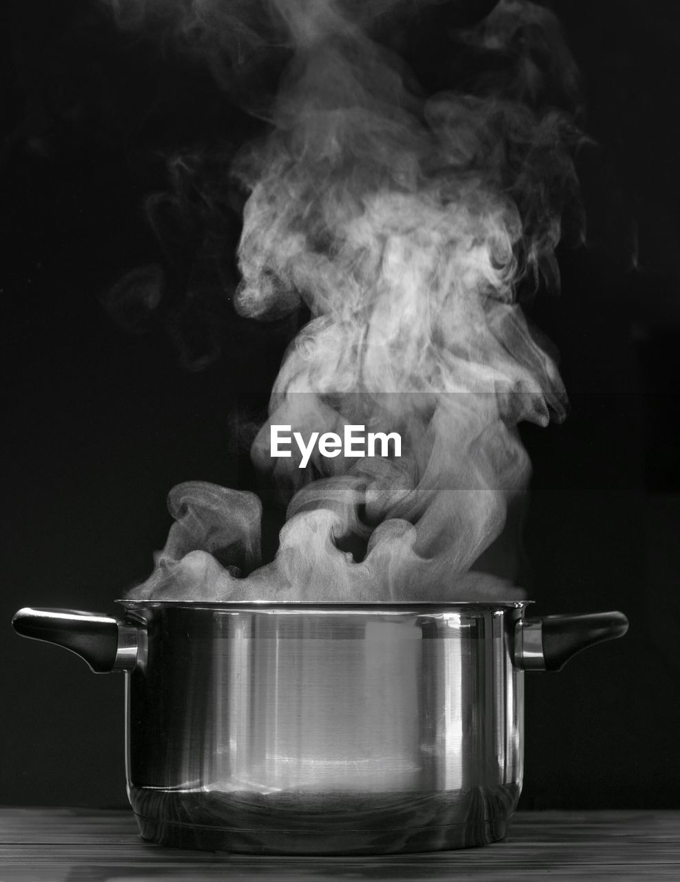 Steaming pot on black background. smoke above boiling soup pot.