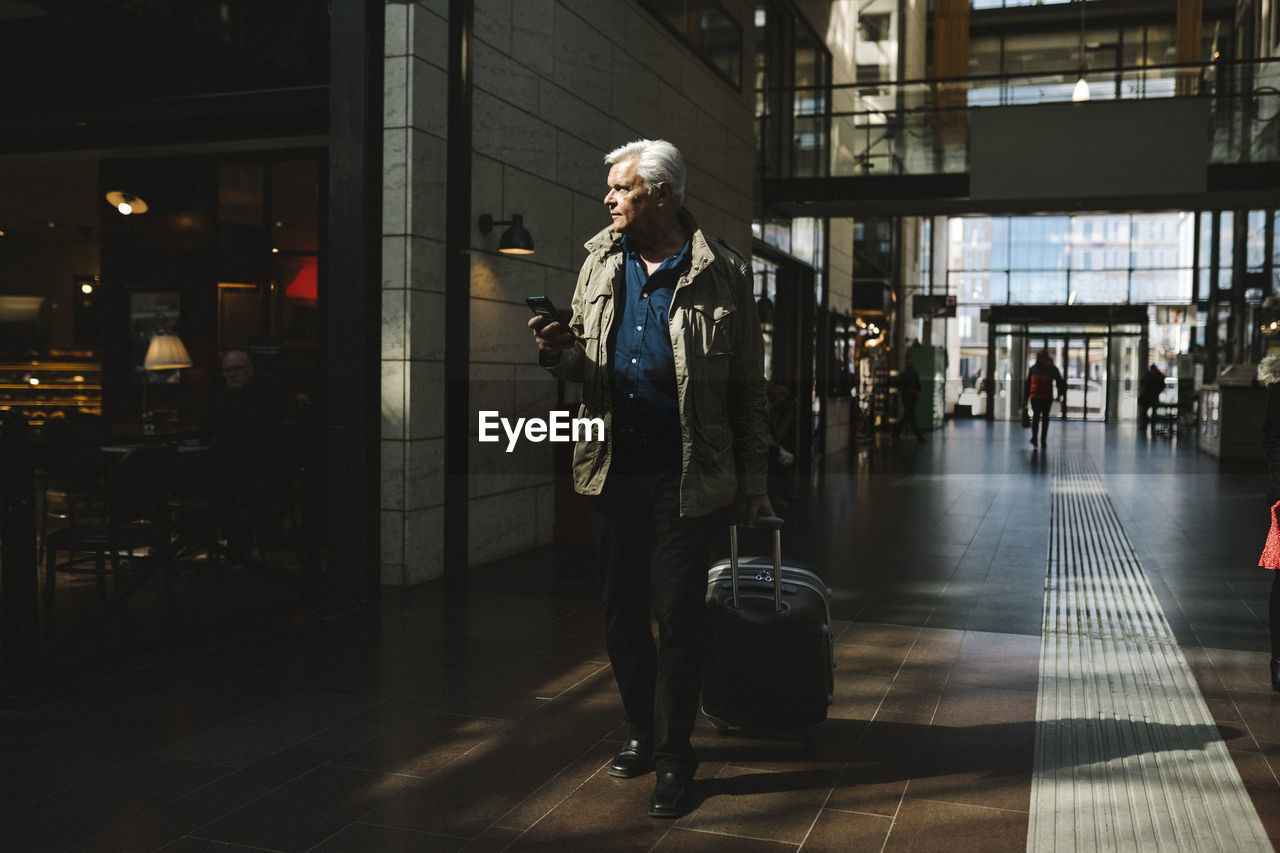 Businessman pulling wheeled luggage while walking at railroad station