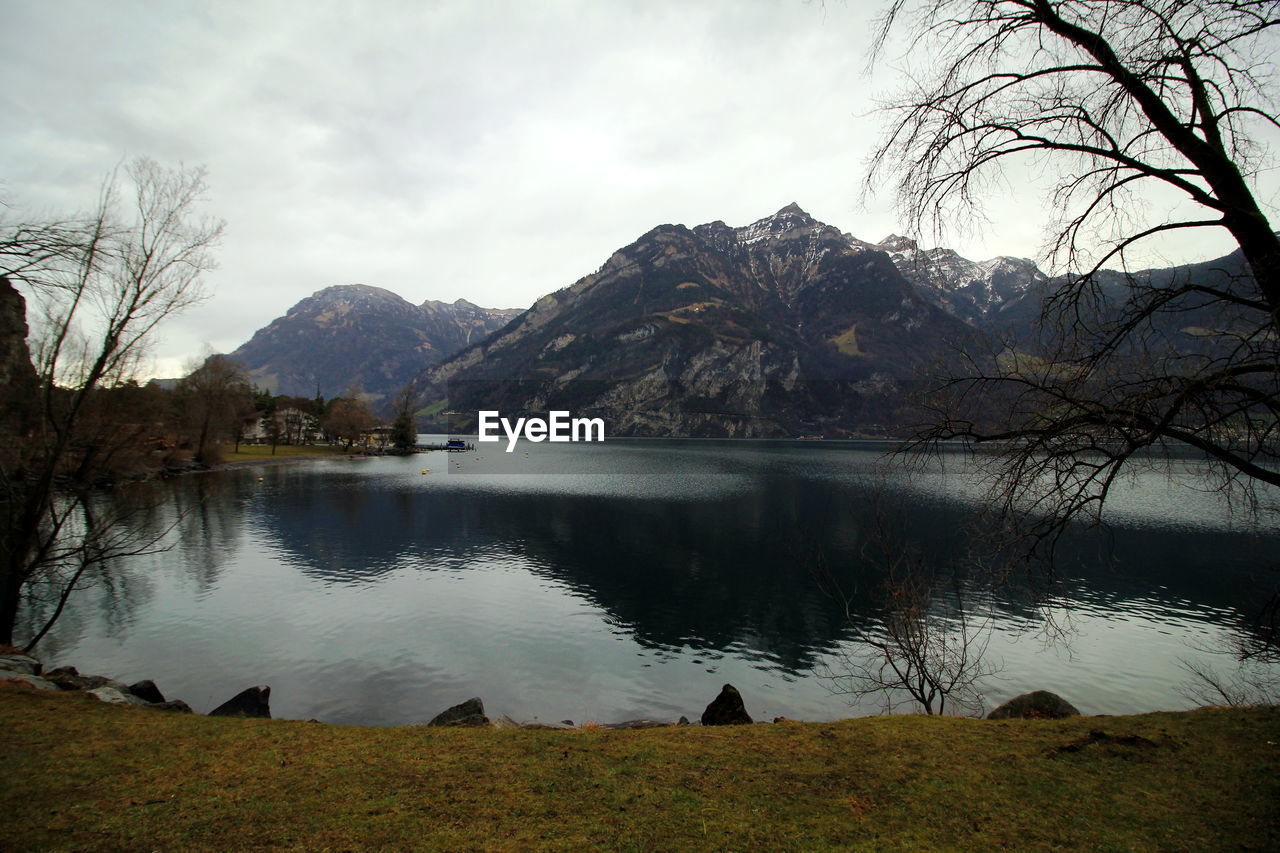 SCENIC VIEW OF LAKE BY MOUNTAIN AGAINST SKY