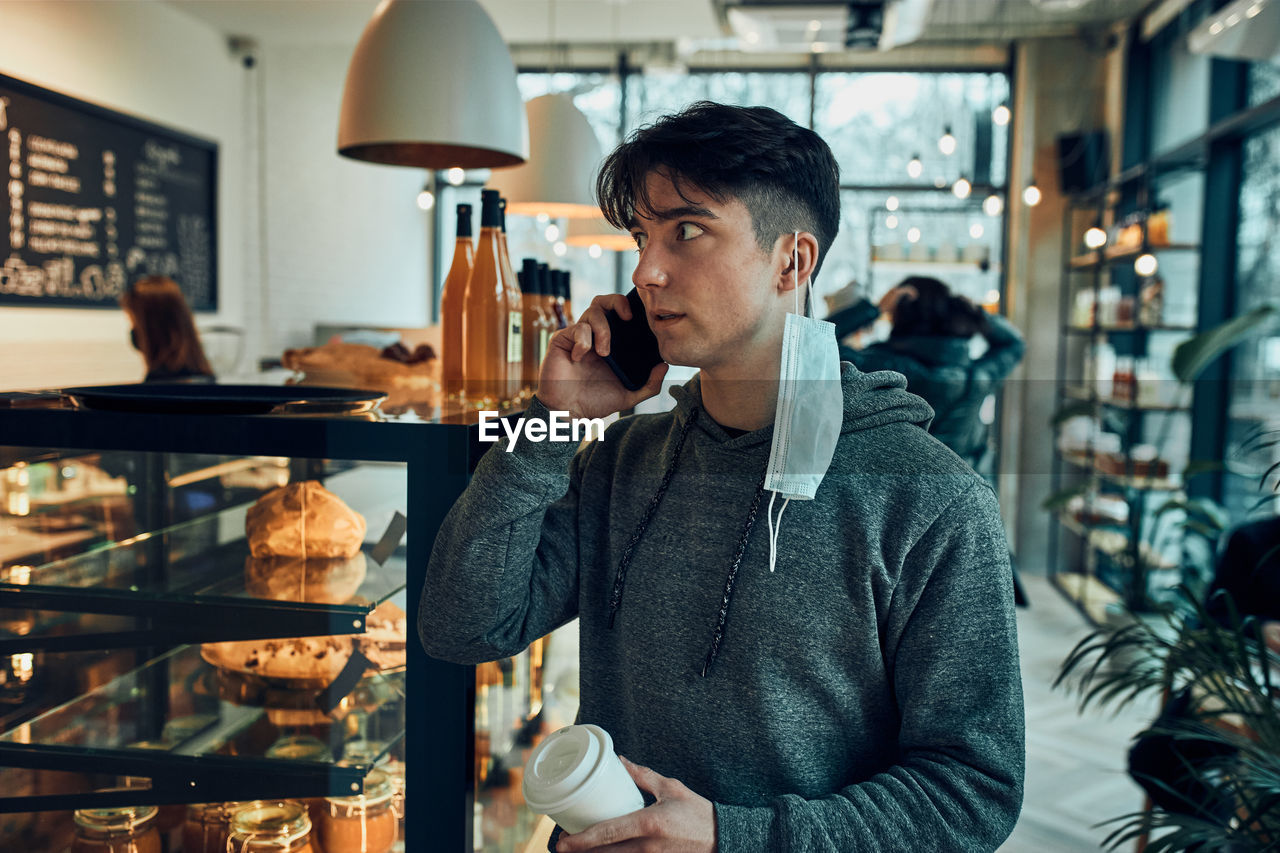 Man talking on phone at cafe, having important phone call, answering call, chatting by mobile phone