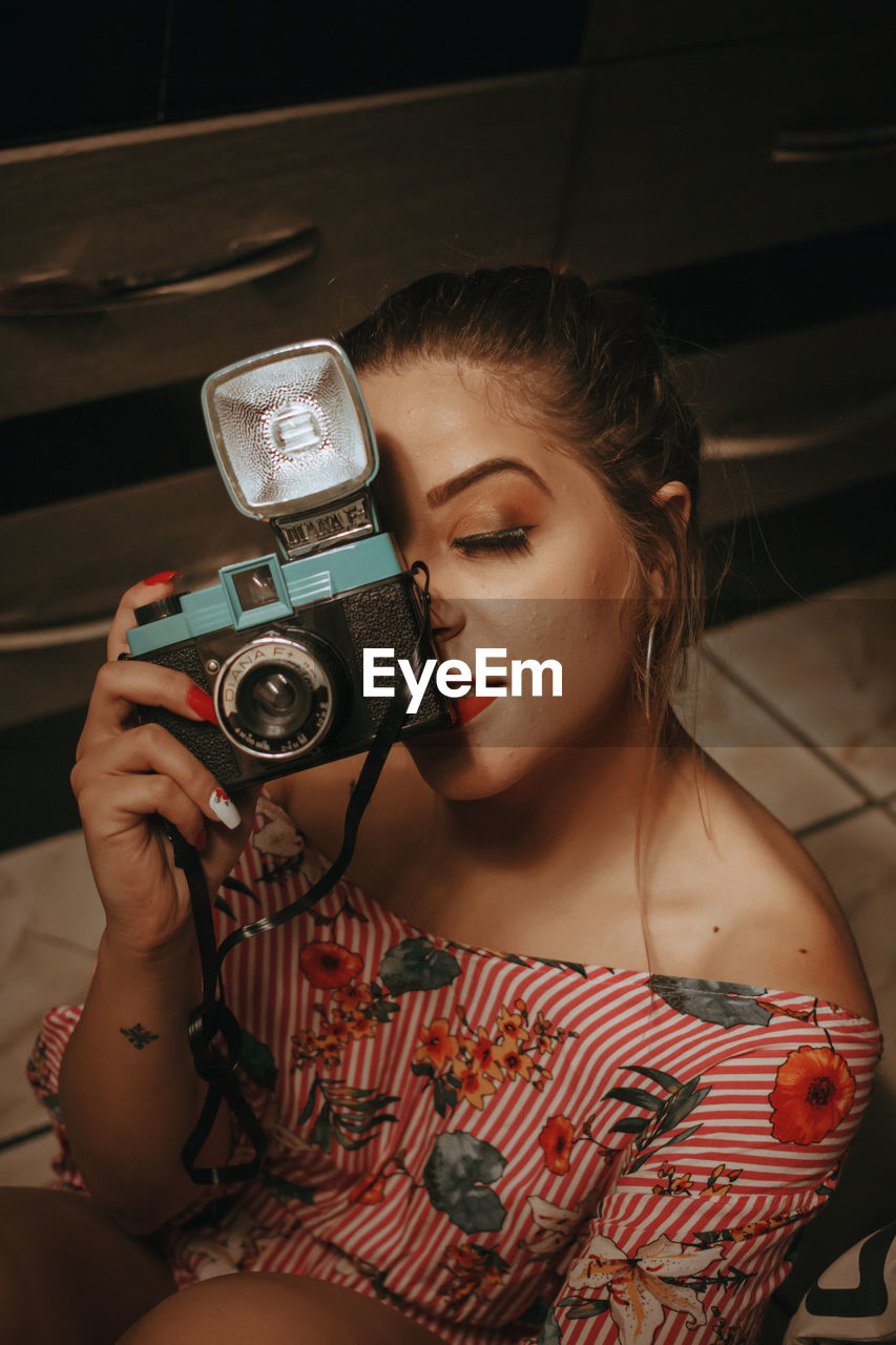 PORTRAIT OF YOUNG WOMAN HOLDING CAMERA