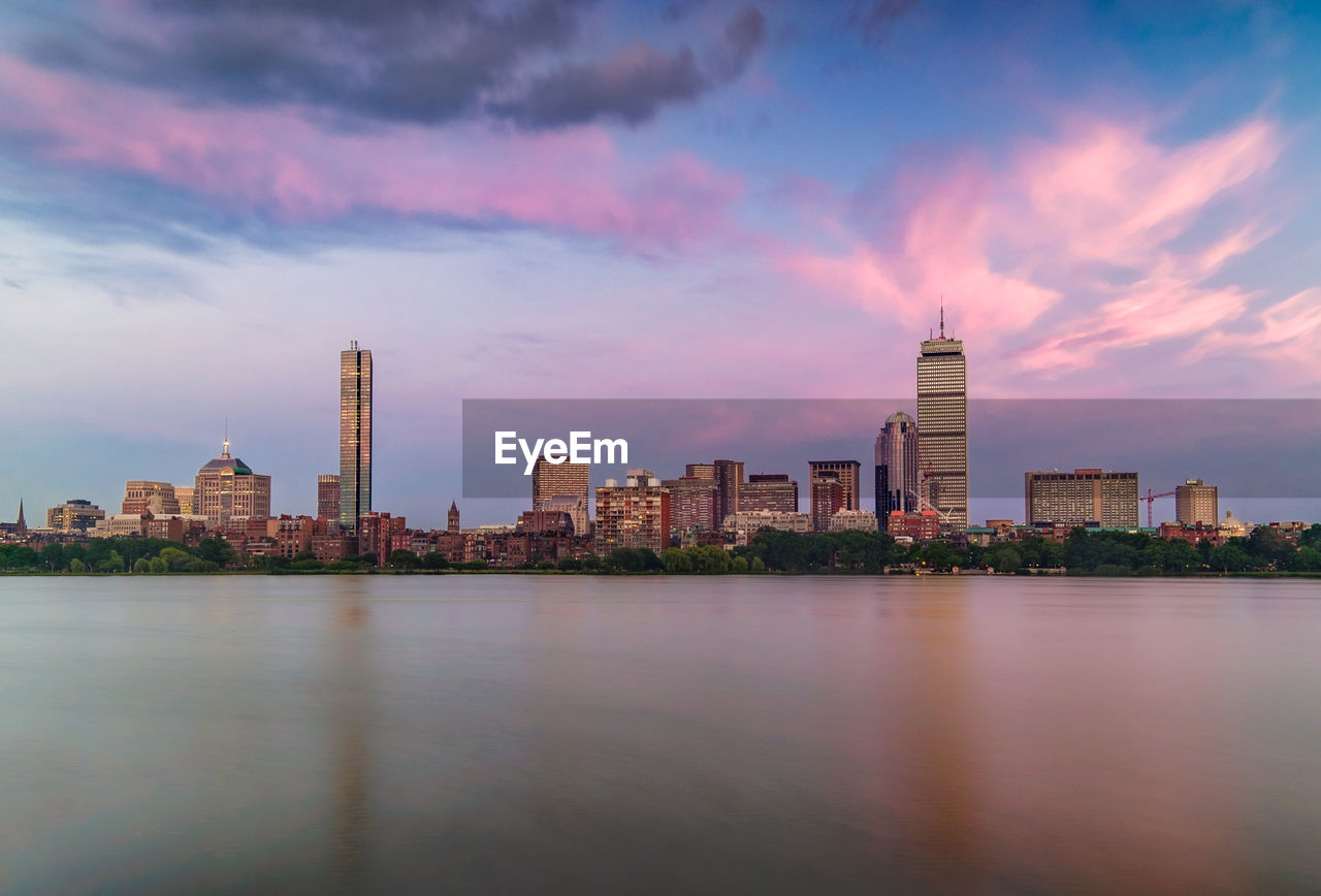 City at waterfront against cloudy sky