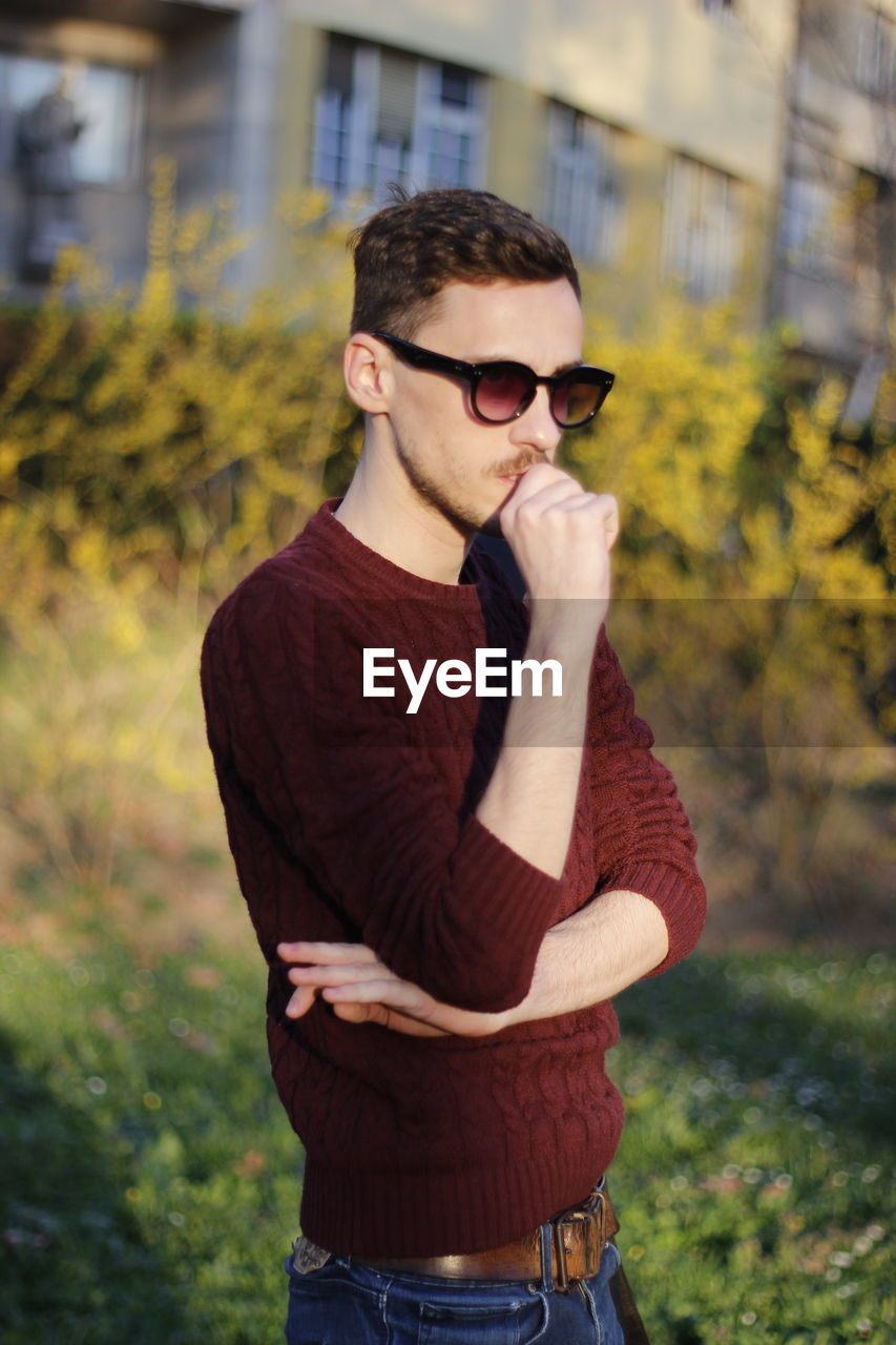 Thoughtful man wearing sunglasses standing outdoors