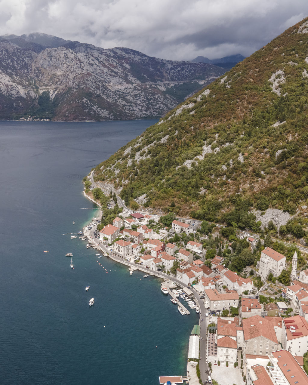 HIGH ANGLE VIEW OF TOWNSCAPE BY SEA AGAINST MOUNTAINS