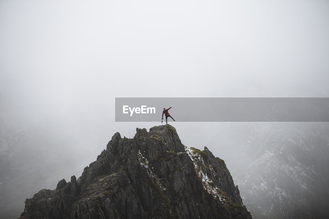 Man on rock in mountains against sky