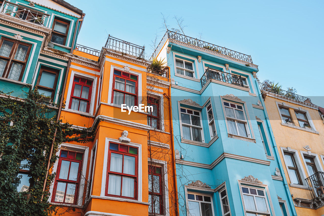 From below bright multicolored houses located against cloudless blue sky on sunny summer day on street of balat district in istanbul, turkey