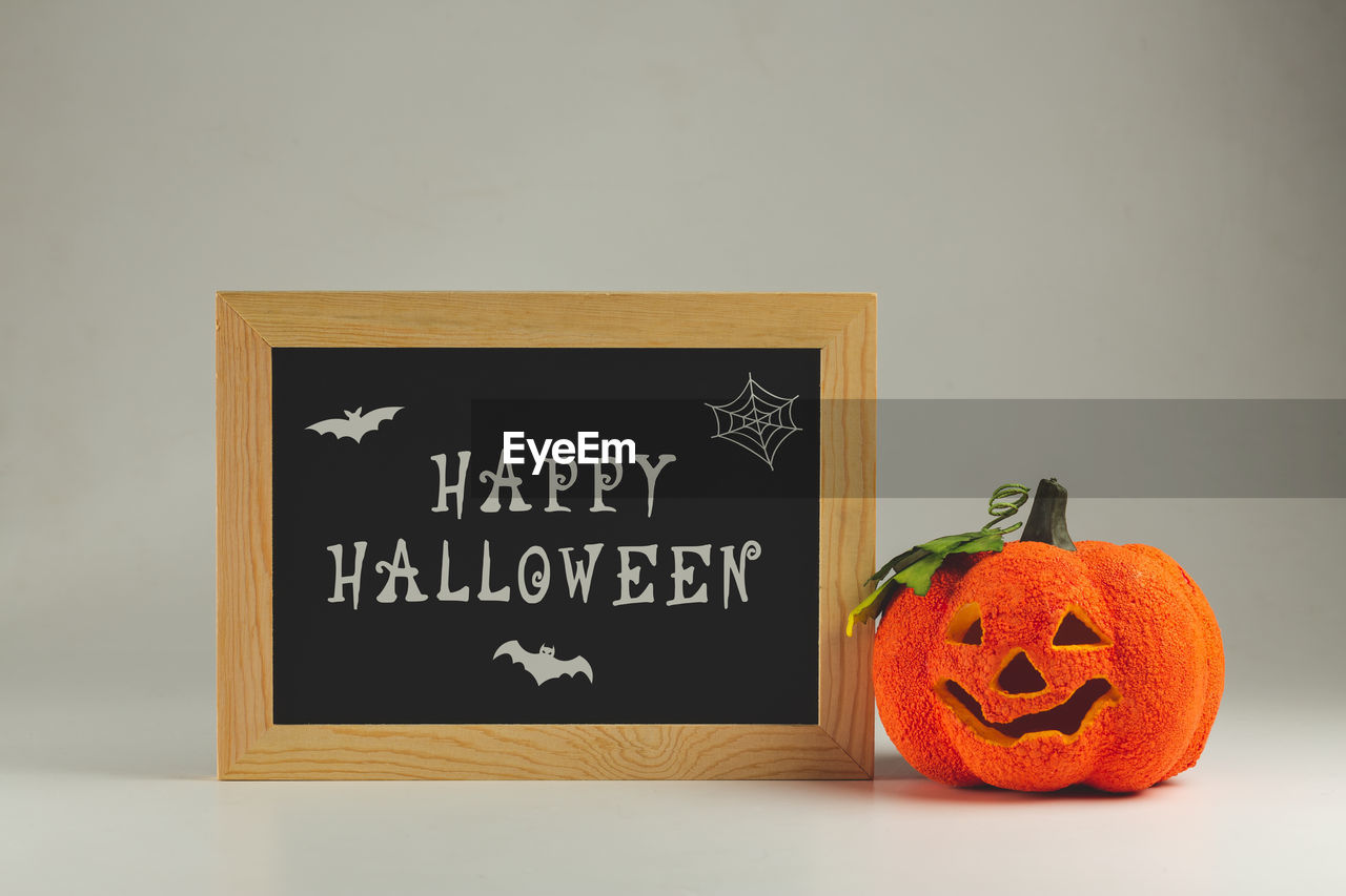 Happy halloween written on a chalkboard and fake curved pumpkin - halloween background