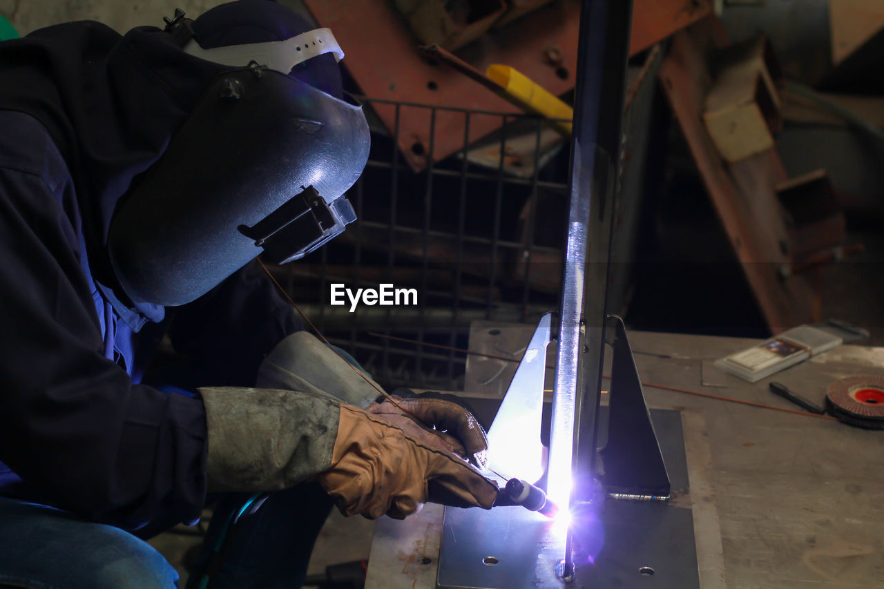 Side view of worker welding metal in workshop