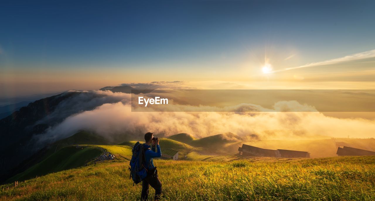 High angle view of man standing on mountain against sky during sunset
