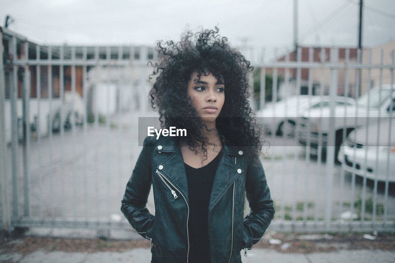 PORTRAIT OF YOUNG WOMAN STANDING OUTDOORS