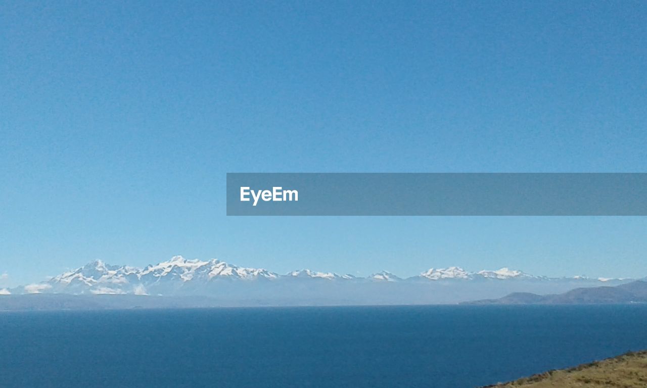SCENIC VIEW OF SEA AND SNOWCAPPED MOUNTAINS AGAINST BLUE SKY