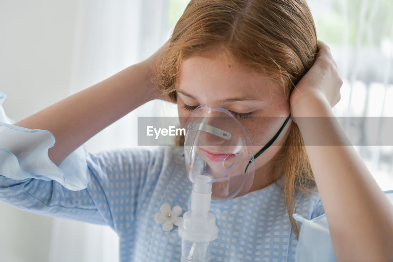 Close-up of girl wearing oxygen mask in hospital ward