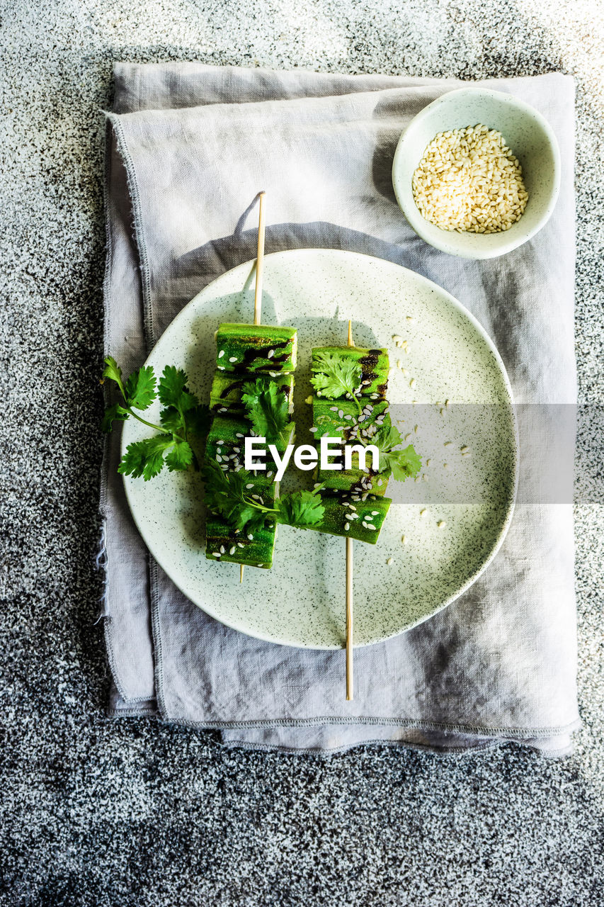 Bbq slices of okra with sesame seeds, coriander and soy sauce served on the plate