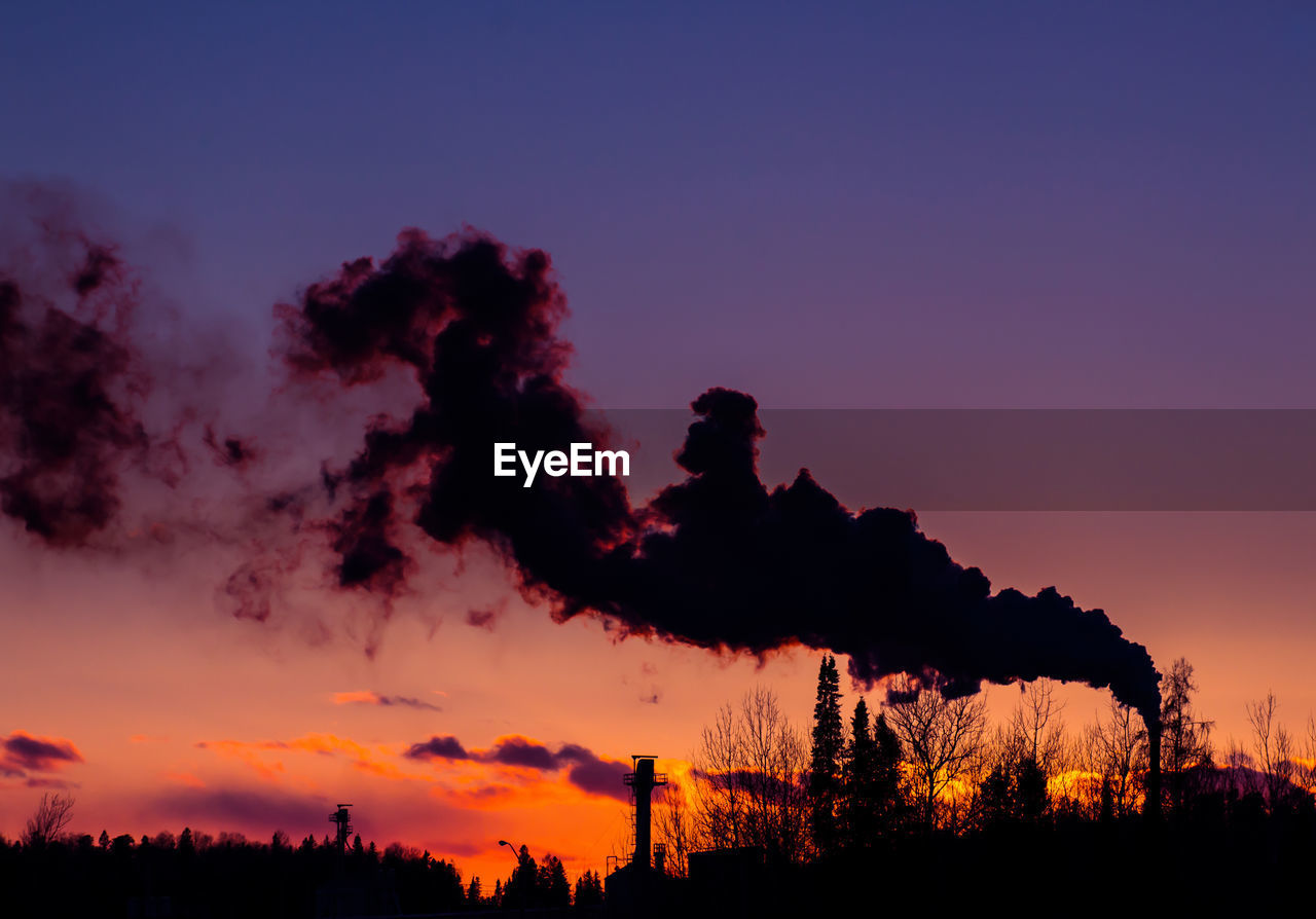 Smoke emerging from chimney on silhouette landscape