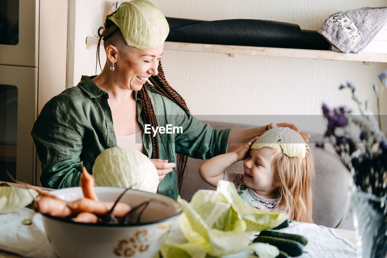 Happy vegan family mom and baby daughter cooking together and having fun on kitchen. family cooking