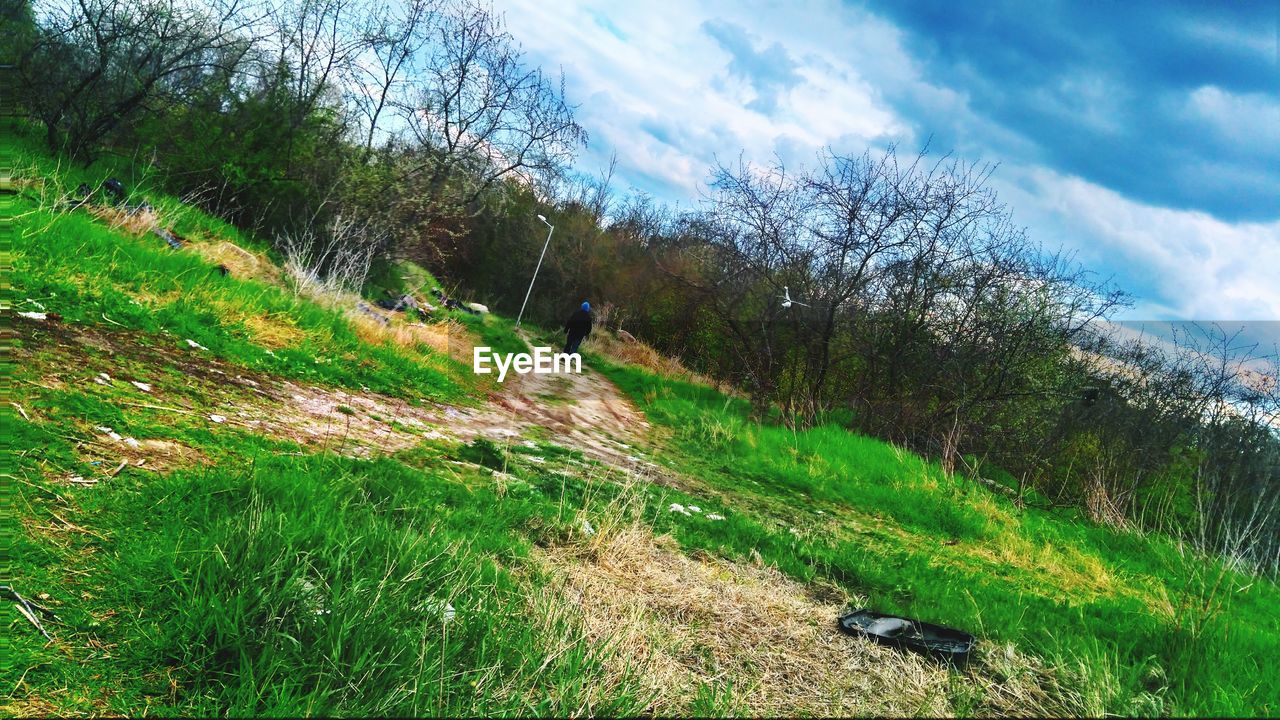 SCENIC VIEW OF GRASSY FIELD BY ROAD AGAINST SKY